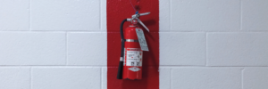 red fire extinguisher hanging on a white concrete wall