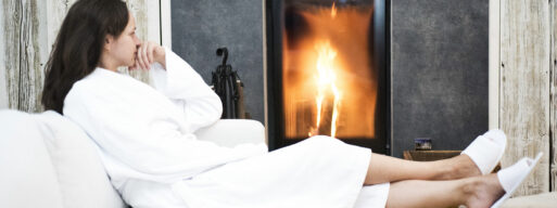 Women in Bath robe beside a nice fireplace and enjoying the warmth