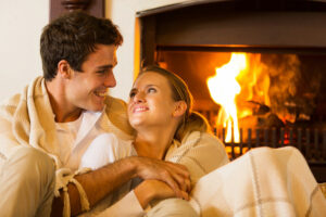 Couple wrapped in blankets to be cozy by the fireplace