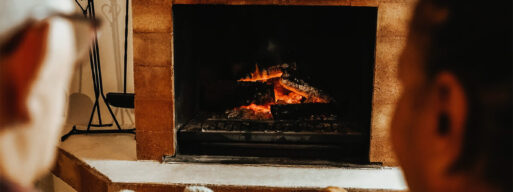 Multiracial senior friends by wood fireplace warming inside rural living room. oliday vacations